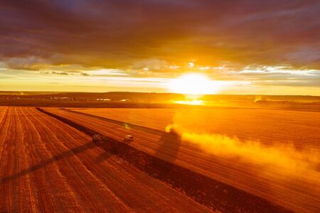 Combine harvester harvests wheat in the field at sunset in autumn in Russia. view from a height of equipment and field.の写真素材