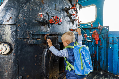 little boy tourist considers controls Old black steam locomotive in Russia, Moscow railway station.の写真素材