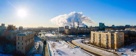 power plant pipes and cooling towers on the background of the panorama of the winter city against...