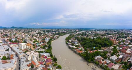 Panoramic summer view of the city of Kutaisi, Georgia. Blue sky with clouds. River Rioni and old houses with Red roofs. Mountains in the distance.の写真素材
