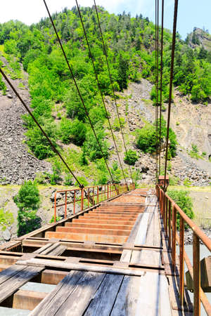 Suspension bridge. Old rusty road bridge over a mountain river in Georgiaの写真素材