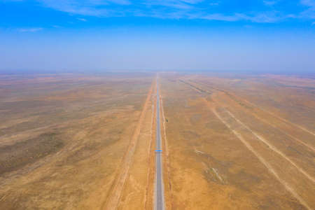 amazing panorama of the steppe and a straight line of the highway through the sandy desert in the Astrakhan region in Russiaの写真素材