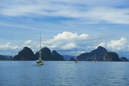 Three boats sailing through tropical group of islands with limestone caves inside in Ao Phang-Nga National Park, Andaman Sea, Thailand. November 12, 2017の写真素材