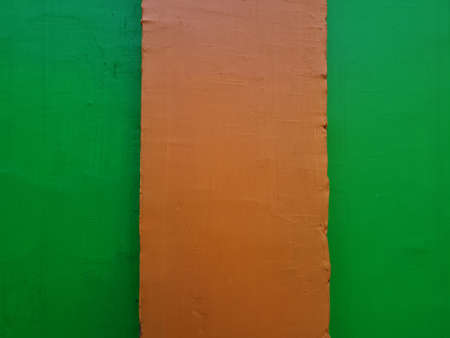 The background of the image of the building wall is green paint combined with orange paint colorの写真素材