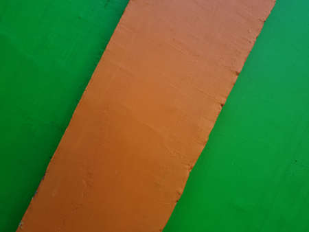 The background of the image of the building wall is green paint combined with orange paint colorの写真素材