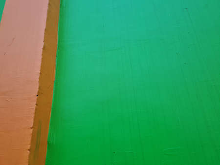 The background of the image of the building wall is green paint combined with orange paint colorの写真素材