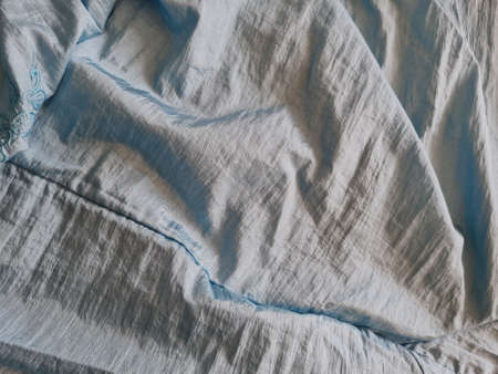 Abstract background textured with shiny light blue fabric with irregular creases and shadows as a combinationの写真素材