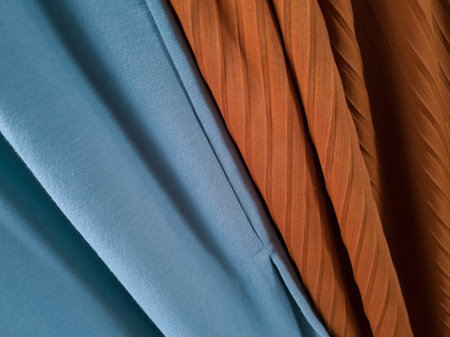 Abstract cloth background with orange and light blue textures exposed to sunlight so that shadows...