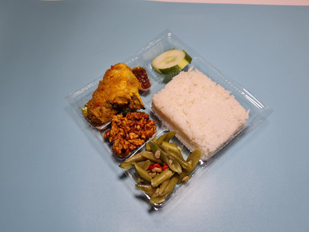 Typical dishes from Indonesia are mixed rice with fried chicken, fried chili sauce, stir-fried long beans and sliced cucumberの写真素材