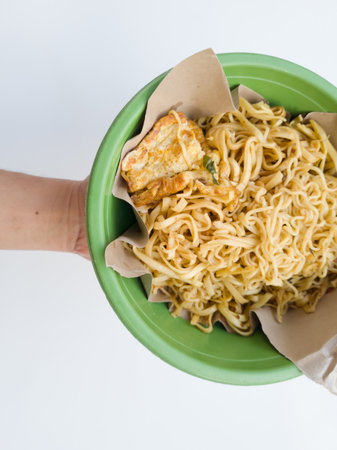 Fried noodles covered in paper in a round green containerの写真素材