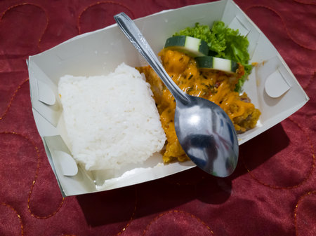 Chicken rice sprinkled with cheese mayonnaise in a white paper containerの写真素材