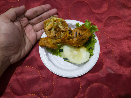 Sweet and sour fried chicken in a white container with cucumber slices and green lettuceの写真素材