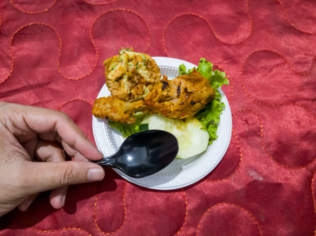 Sweet and sour fried chicken in a white container with cucumber slices and green lettuceの写真素材