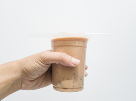 Hand holding a plastic cup of iced coffee isolated on white backgroundの写真素材