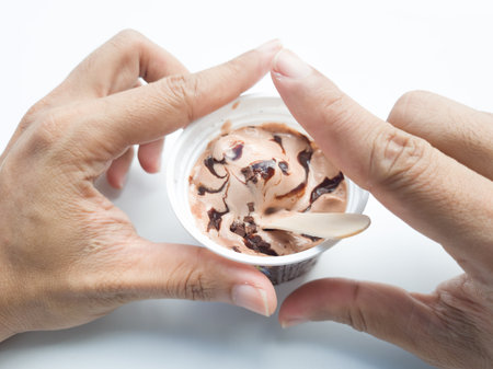 Close up of hand holding ice cream in plastic cup on white backgroundの写真素材