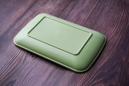 Place a green container made of plastic on wood