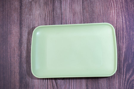 Place a green container made of plastic on wood
