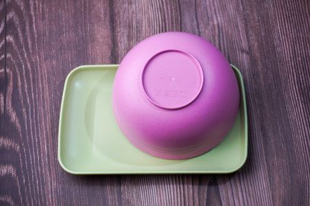 Food containers made of plastic include bowls, plates and square plates in pink and green on woodの写真素材