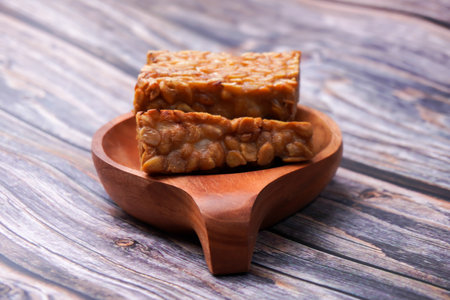 Fried tempeh in a container on a wooden tableの写真素材