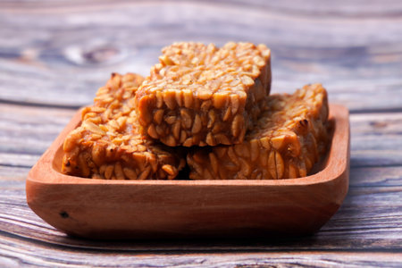 Fried tempeh in a container on a wooden tableの写真素材