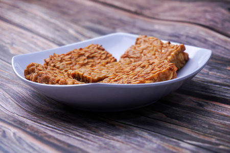 Fried tempeh in a container on a wooden tableの写真素材