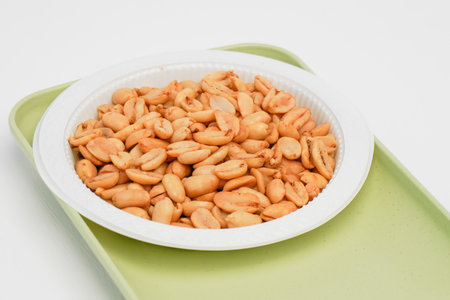 Peanuts in a white plate on a green plate on a white backgroundの写真素材