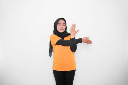 Expression of warming up gymnastics by crossing the arms of an Asian woman wearing a hijab