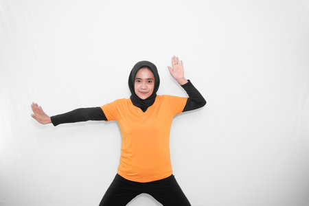 Warm-up expression of gymnastics bending hands to shoulders and one arm straight Asian woman wearing hijabの写真素材