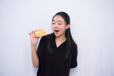 Expression of Asian woman in black dress holding bread on white backgroundの写真素材