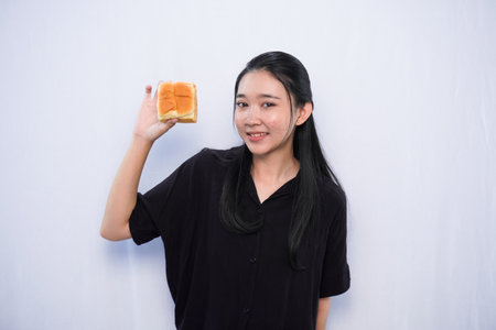 Asian woman in black dress expression showing bread on white backgroundの写真素材