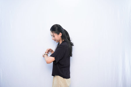 Asian woman looking at watch on white background