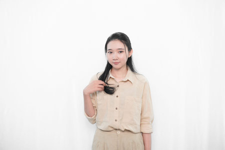Expression of Asian woman in a white shirt smiling and holding hairの写真素材
