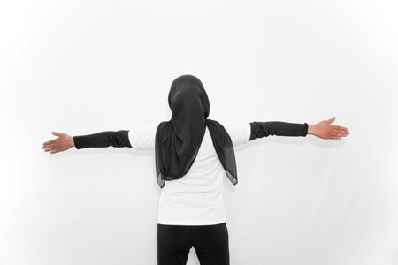 A woman in a hijab does gymnastics, facing backwards with two hands to the side.の写真素材
