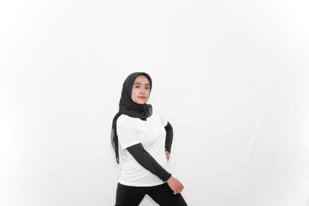 A woman in a hijab doing gymnastics, one hand on her waist, one straight down