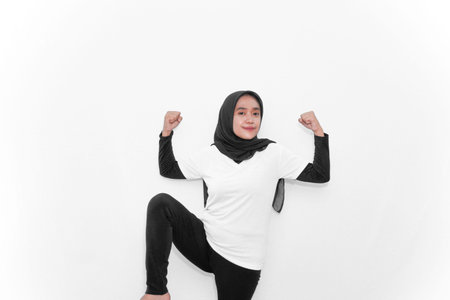 A woman in a hijab doing gymnastics, clenching her fists to show strength or health.