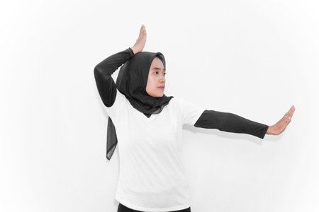 A woman in a hijab doing gymnastics, one hand above her head, one hand straight to the side