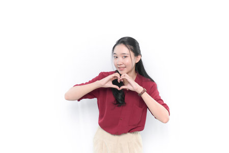 Smiling Indonesian Asian woman in red making love signの写真素材