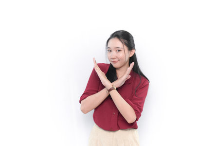 Smiling Indonesian Asian woman in red shirt giving a sign of disagreementの写真素材