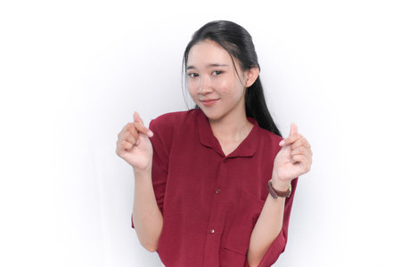 Asian woman in red dress smiling and making love signの写真素材