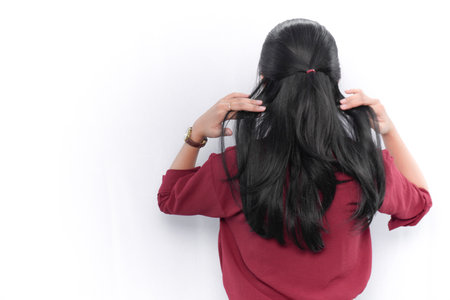 Indonesian Asian woman in red dress holding her hair seen from behindの写真素材
