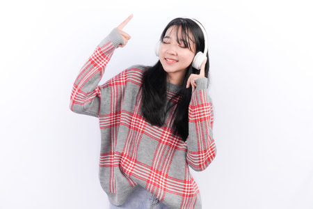Asian woman wearing red checkered sweater wearing headset listening to music
