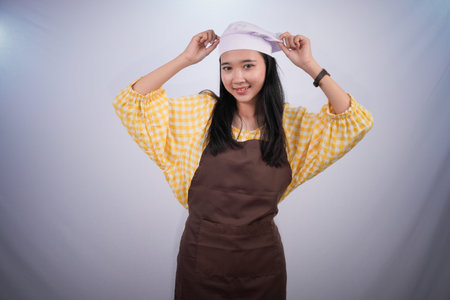 Asian woman wearing chef's clothes is holding a hatの写真素材