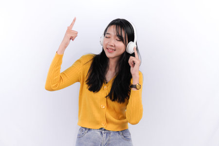 Asian woman wearing yellow shirt wearing headset listening to music