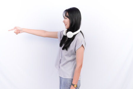 Asian woman wearing gray shirt with headset necklace pointing forwardの写真素材