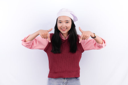 Indonesian woman in pink shirt and chef's hat smiling pointing downの写真素材