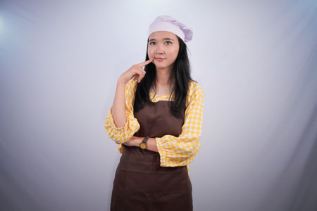 Asian Indonesian woman wearing chef's uniform thinking about cooking ideasの写真素材