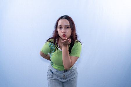 Asian Indonesian woman in green shirt is blowing on her hand