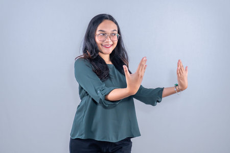 Asian Indonesian woman wearing green shirt with glasses smiling and showing her fingers