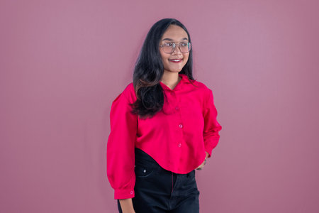 Asian woman in red shirt smiling and putting her hands on her hipsの写真素材