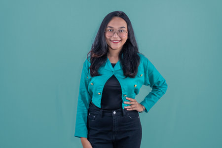 Asian woman in turquoise dress smiling and putting her hands on her hipsの写真素材